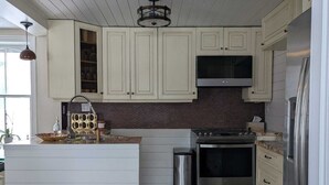A kitchen with white cabinets, a stainless steel stove, and a large island with a sink.