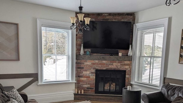 A living room with a brick fireplace, a flat-screen TV, and two dark brown sofas.