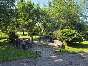An outdoor seating area with wicker furniture, a stone table, and a small fountain. - Private corner lot nested in the heart of the horse and trail capitol of Ontario (East Gwillimbury)