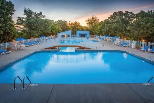 A swimming pool with lounge chairs and a small building structure.