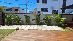 A backyard with a wooden deck, palm trees, and a white wall with barbed wire. - Amazing 4-bedroom villa in Grand Baie perfect for your getaway (Grand Baie)