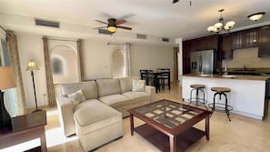 A modern living room with a sofa, coffee table, and dining area. - Rainbow Rise: Oceanfront, Sunsets, Secluded beach, Backup Generator! (Cupecoy)