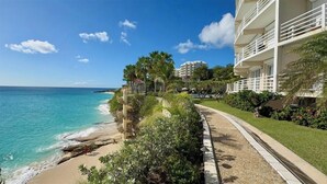 Hotel ved stranden med pool, palmer og havudsigt.