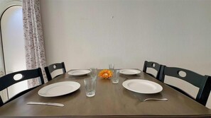 A dining table set with plates, glasses, and cutlery, surrounded by chairs. - Rainbow Rise: Oceanfront, Sunsets, Secluded beach, Backup Generator! (Cupecoy)
