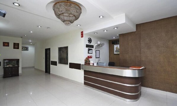A reception area with a modern design, featuring a reception desk, a chandelier, and a wall-mounted clock. - HOTEL DREAMZ RESIDENCY (Karnal)
