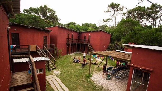 Ein rotes Gebäude mit einer Holztreppe, einer überdachten Außenbereich-Sitzgelegenheit und einem kleinen Fenster.