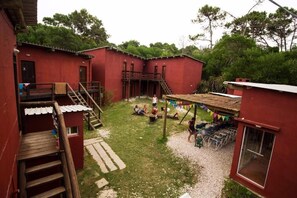A red building with a wooden staircase, a covered outdoor seating area, and a small window. - Posada La Pedrera (La Pedrera)