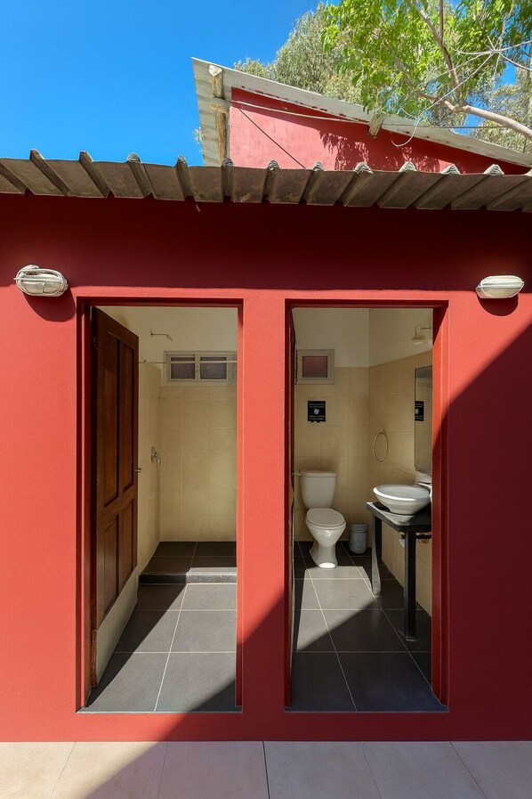 A compact bathroom with a toilet and sink, a small window, and a door. - Posada La Pedrera (La Pedrera)