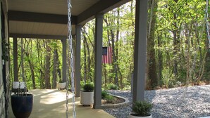 Eine überdachte Veranda mit einer weißen Schaukel, einem Blumentopf und einer amerikanischen Flagge.