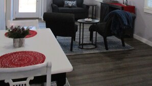Ein Wohnzimmer mit Deckenventilator, Kamin, Wandfernseher und einem Essbereich mit Tisch und Stühlen.