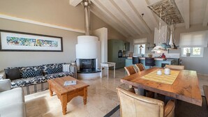 A spacious living area with a fireplace, a dining table, and a sofa. - Villa di Sogno - Montecristo Apartment (Capoliveri)