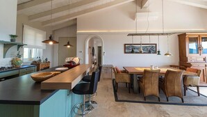 A modern kitchen with a central island, bar stools, and a dining area with a wooden table and chairs. - Villa di Sogno - Montecristo Apartment (Capoliveri)