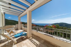 A balcony with a view of the sea and hills, a table, and a chair. - Villa di Sogno - Montecristo Apartment (Capoliveri)