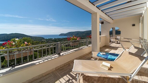 A balcony with a view of the sea and hills, a table, and lounge chairs. - Villa di Sogno - Montecristo Apartment (Capoliveri)