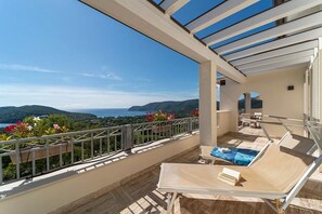A balcony with a view of the sea and hills, a table, and lounge chairs. - Villa di Sogno - Montecristo Apartment (Capoliveri)