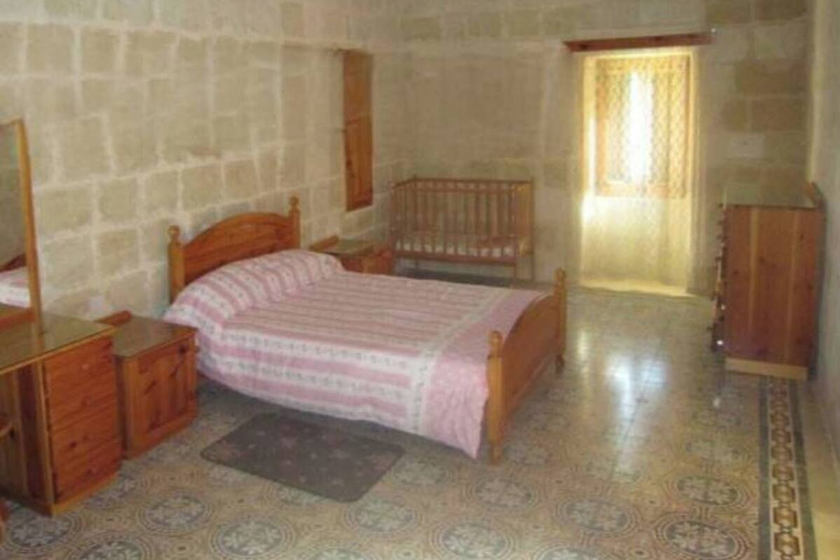 A bedroom with a bed, a dresser, a mirror, and a window.