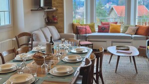 A dining area with a table set for four, chairs, and a sofa with cushions. - Villa Mifa 5 minutes from the center with Lagoon Pool (Sarlat-la-Canéda)
