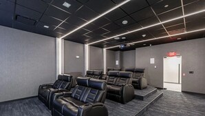 Moderni kotiteatterihuone, jossa on useita kallistettavilla selkänojilla varustettuja istuimia, projektori ja matolla peitetty lattia.