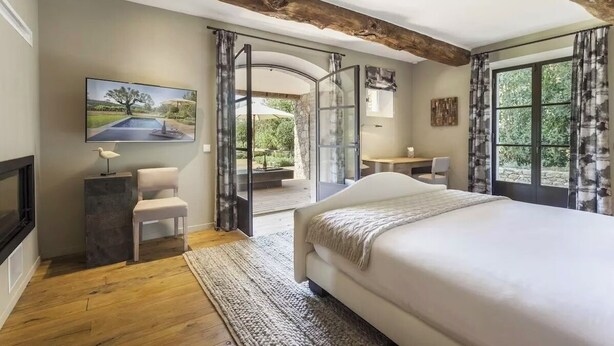 Un dormitorio con una cama grande, televisión y vistas al exterior a través de un ventanal.