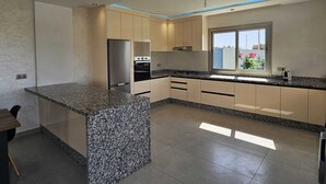 A modern kitchen with granite countertops, stainless steel appliances, and a large window providing natural light. - Villa in Berkane with swimming pool, not overlooked (Berkane)
