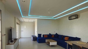 A modern living room with a blue sofa, a wooden coffee table, and a dining area with a table and chairs. - Villa in Berkane with swimming pool, not overlooked (Berkane)