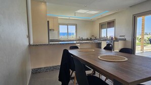 A modern kitchen with a dining area, large windows, and a view of the sea. - Villa in Berkane with swimming pool, not overlooked (Berkane)