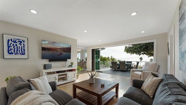 A modern living room with a sofa, coffee table, TV, and artwork on the wall. - Ocean-View Wellness Home | Infrared Sauna + Spa (Summerland)