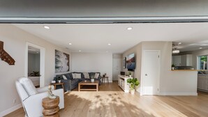A modern living room with a sofa, a chair, a coffee table, and a TV. - Ocean-View Wellness Home | Infrared Sauna + Spa (Summerland)
