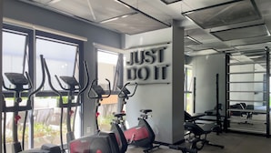 Een sportschool met trainingsapparatuur, grote ramen en een motiverende quote op de muur.