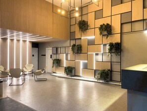 Uma área de recepção moderna com painel de madeira, assentos e balcão de atendimento.