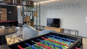 Een moderne kamer met een tafelvoetbaltafel, een pooltafel en een televisie.