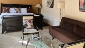 A hotel room with a bed, a sofa, a chair, a small table, and a lamp. - Casa del Tio Hotel Boutique (San Miguel de Allende)