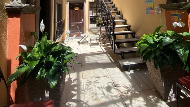 A stone archway leading to a staircase with a view of a building. There are potted plants and a bench. - Casa del Tio Hotel Boutique (San Miguel de Allende)
