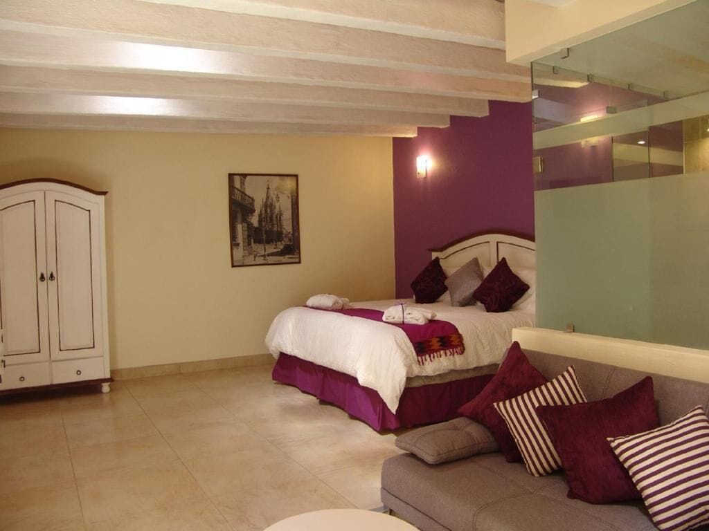 A bedroom with a bed, a sofa, a cabinet, and a painting on the wall.