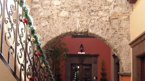 An indoor courtyard with a stone wall, a staircase, and potted plants. - Casa del Tio Hotel Boutique (San Miguel de Allende)