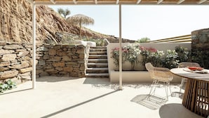 A covered outdoor area with stone walls, a wooden pergola, and a seating area with a table and chairs. - Boutique Villa Ciel Tinos (Tinos)