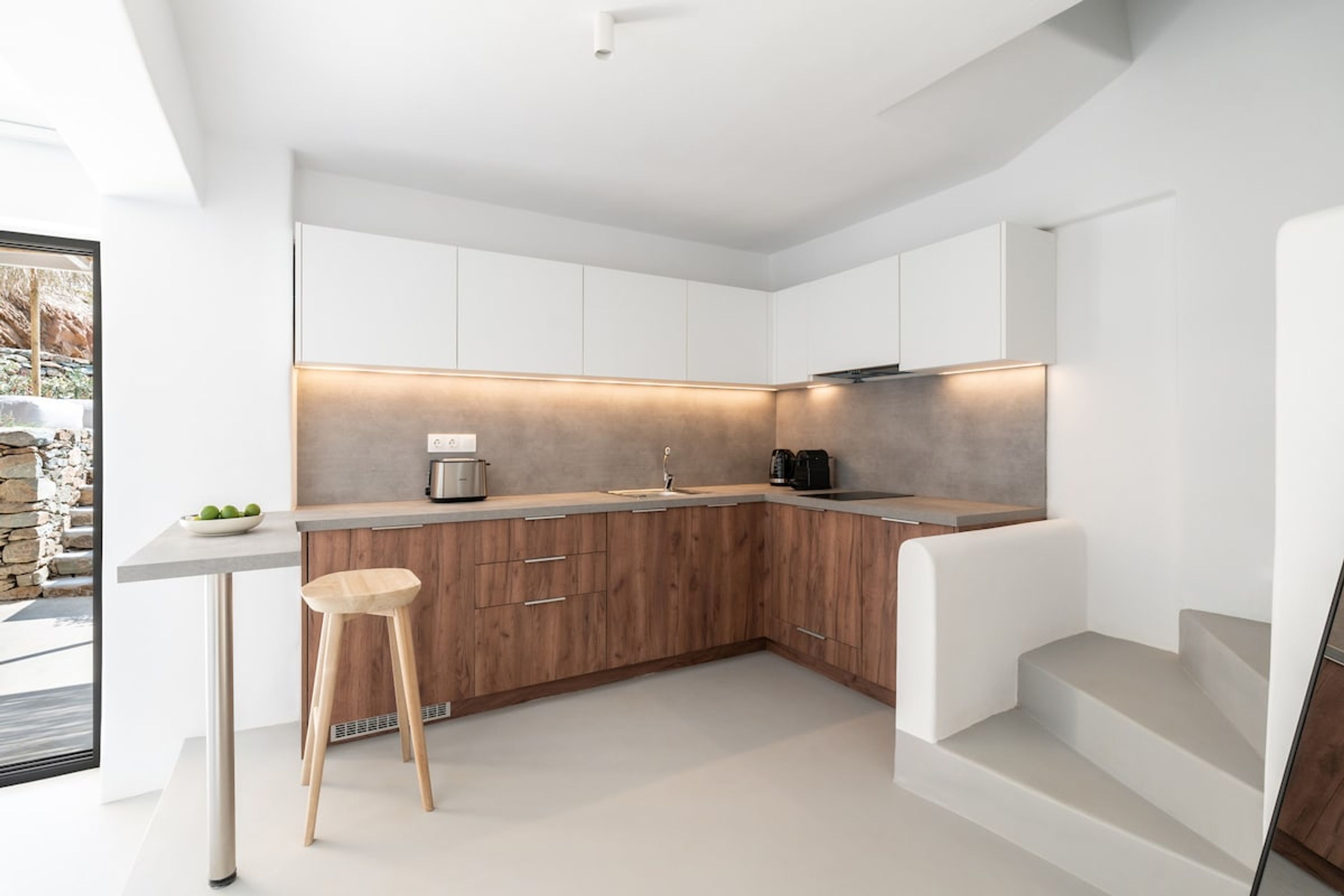 A modern kitchen with white cabinets, a wooden countertop, and a built-in stove.