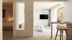 A modern interior with a minimalist design, featuring a sofa, a table with a stool, and a flat-screen TV mounted on the wall. - Boutique Villa Ciel Tinos (Tinos)