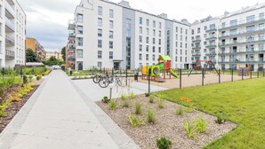Een modern appartementencomplex met een speeltuin, een fietspad en een verzorgde tuin.