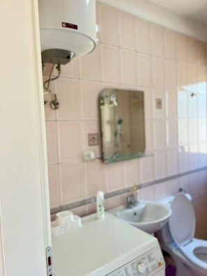 Un baño con lavamanos, espejo y retrete blancos.