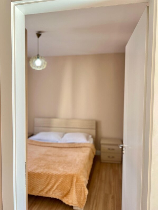 Un dormitorio con cama, mesita de noche y lámpara colgante.