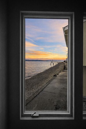 A window with a view of a waterfront during sunset.