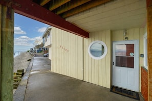 Un edificio costero con puertas numeradas, un ventanal circular y vistas a la playa.