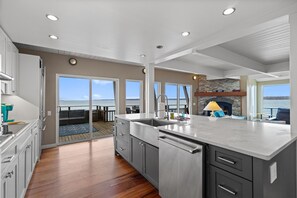 A spacious kitchen with a large island, a stone fireplace, and a view of the ocean. - Bainbridge Beachfront: Seattle Skyline Views (Bainbridge Island)