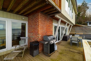Un espacio al aire libre cubierto con chimenea de ladrillo, una parrilla y mobiliario exterior.