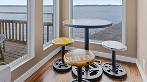 Une pièce dotée de grandes fenêtres donnant sur une plage, une table ronde et un tabouret.