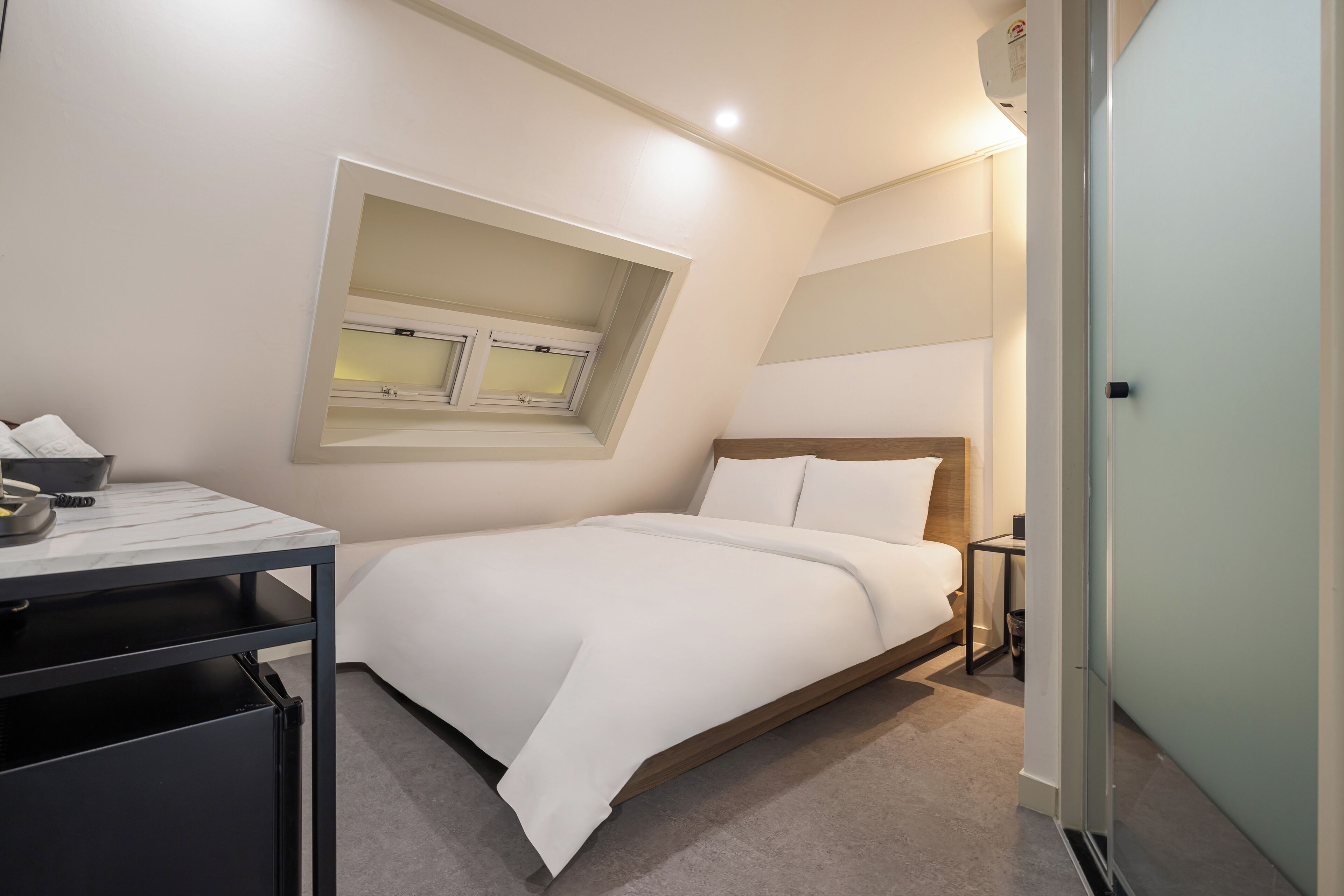 A modern bedroom with a bed, a desk, and a window.
