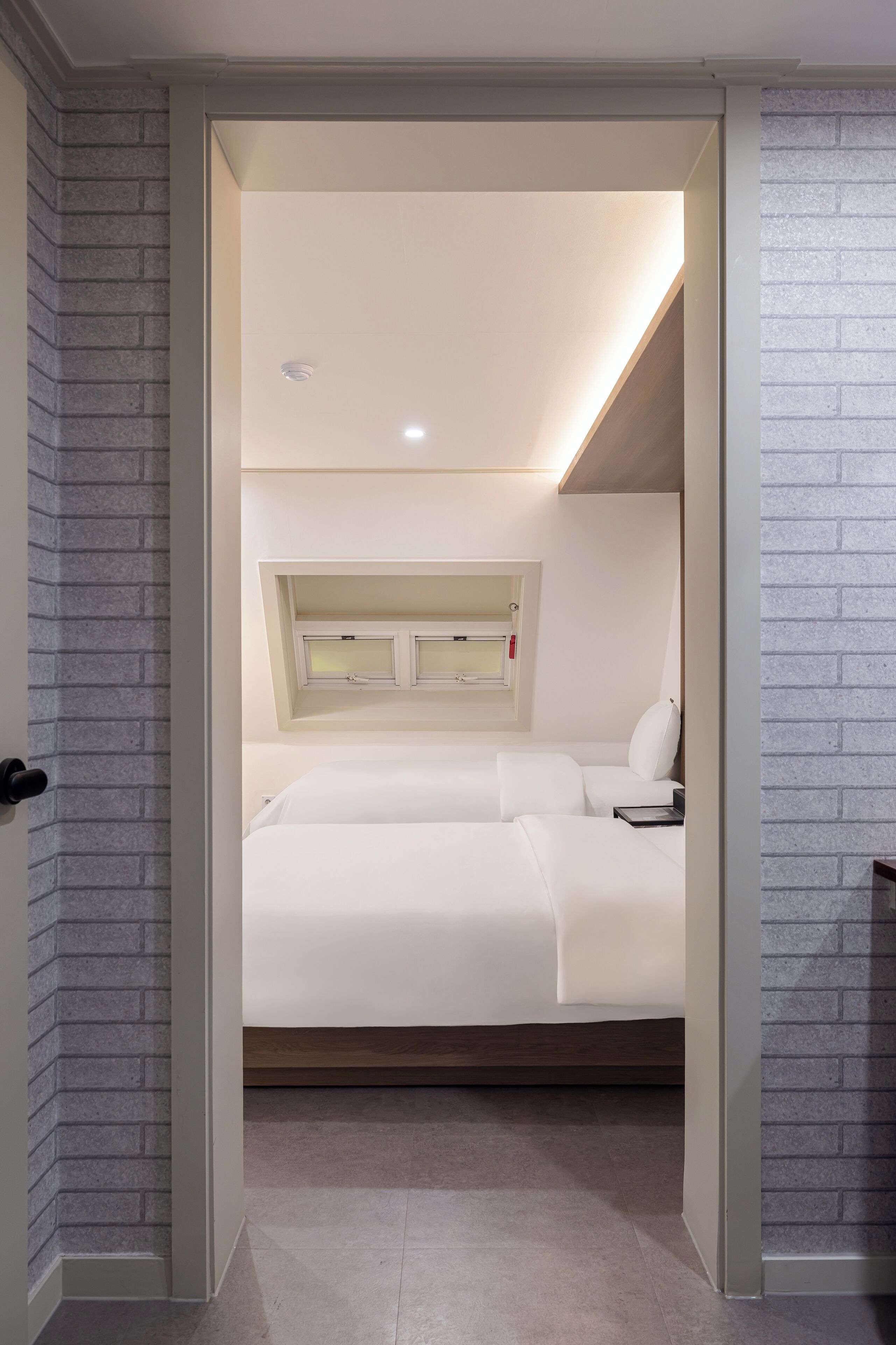A bedroom with a bed, a nightstand, and a window.