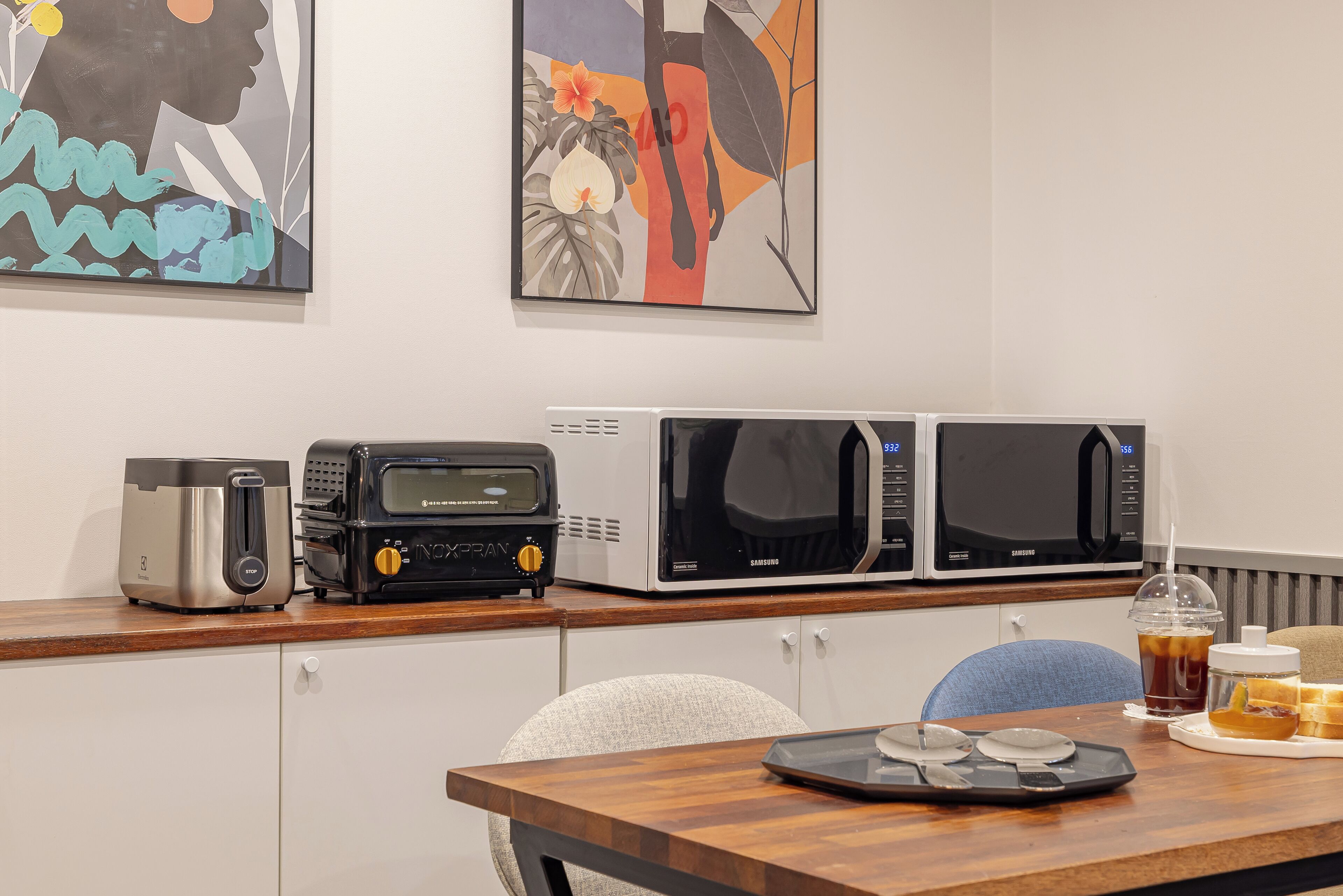 A kitchenette with a toaster, a coffee maker, and two microwaves on the counter.