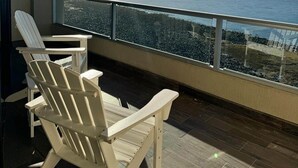 Ein Balkon mit Meerblick, weißen Stühlen und einem Tisch.